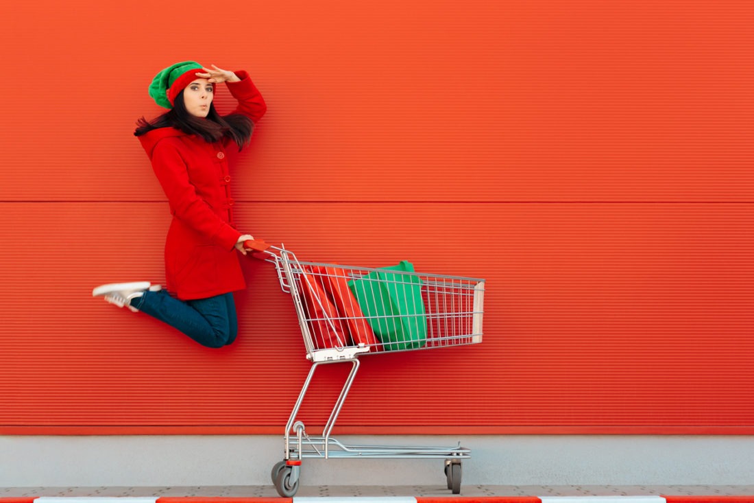woman in elf outfit in front of a red wall with a shopping trolley
